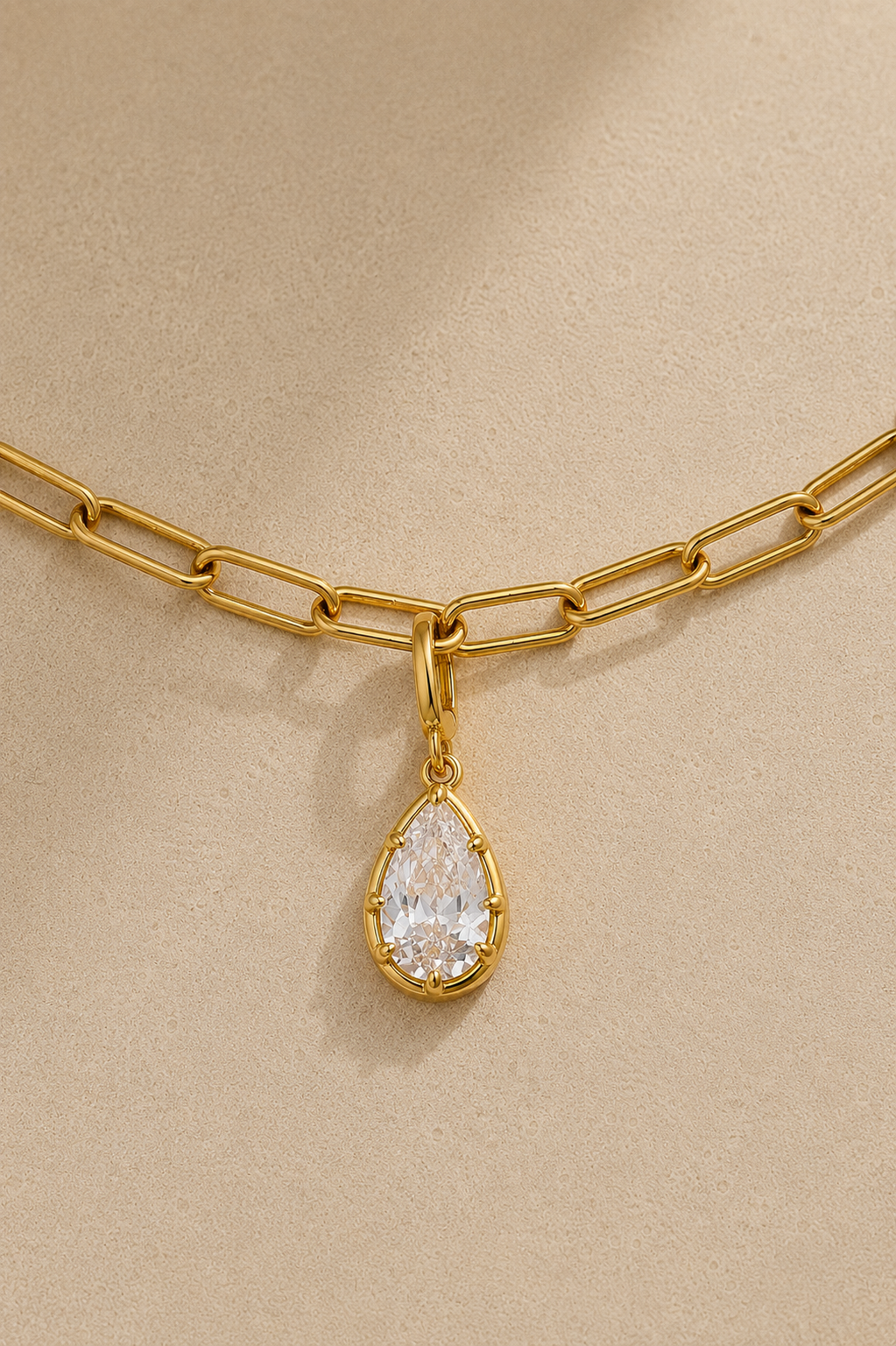 Gold paperclip bracelet with Vittoria gold crystal charm on beige studio background