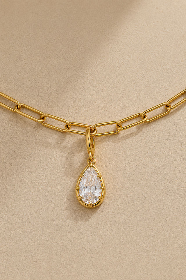Gold paperclip bracelet with Vittoria gold crystal charm on beige studio background