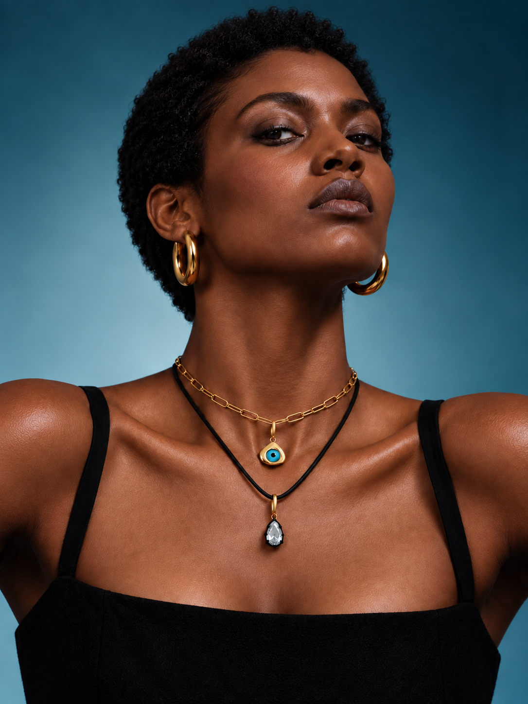 Galleria Armadoro jewellery look featuring bold gold hoops with layered charm necklaces, an evil-eye pendant and a cord necklace.