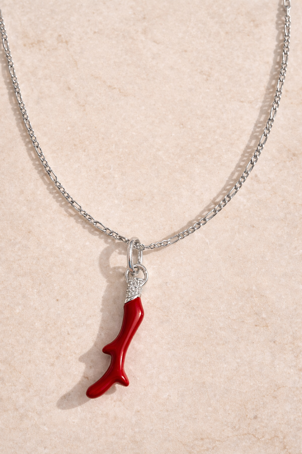 Speira red coral sterling silver necklace with rhodium plating and CZ pavé charm on Scarlett chain, photographed on matte beige marble