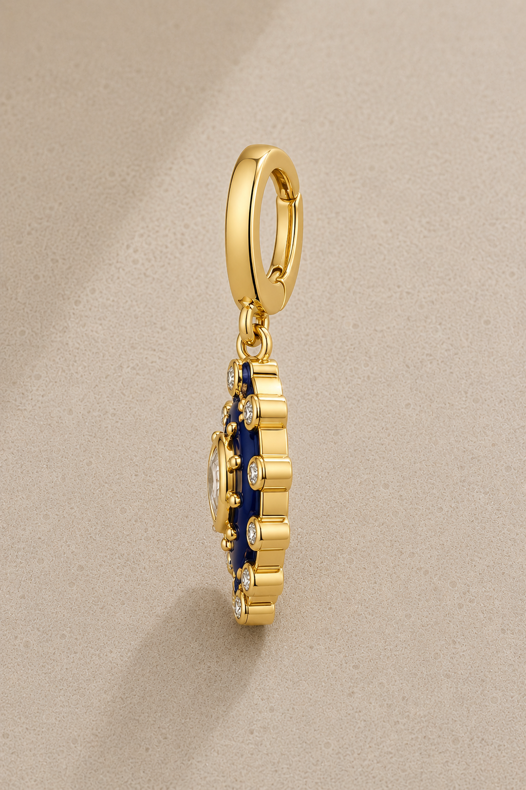 Side view of paisley evil eye gold hook charm with blue enamel and crystals