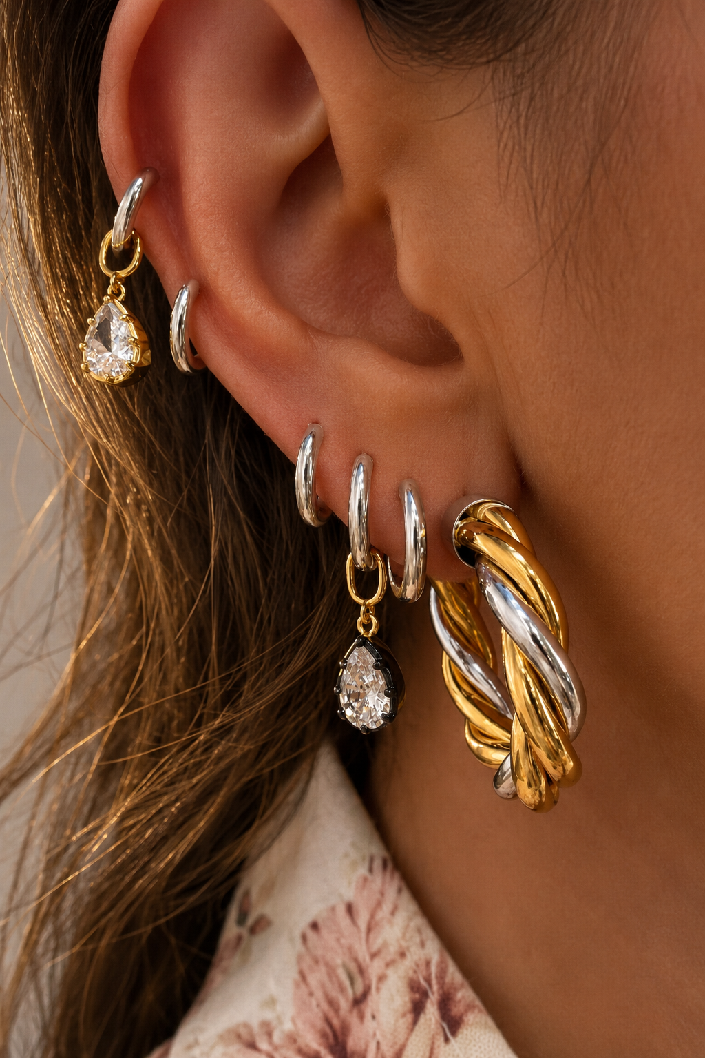 Close-up mixed-metal ear stack with silver huggies, teardrop charms and 3cm Two-Tone Tina hoop earrings in silver and gold.