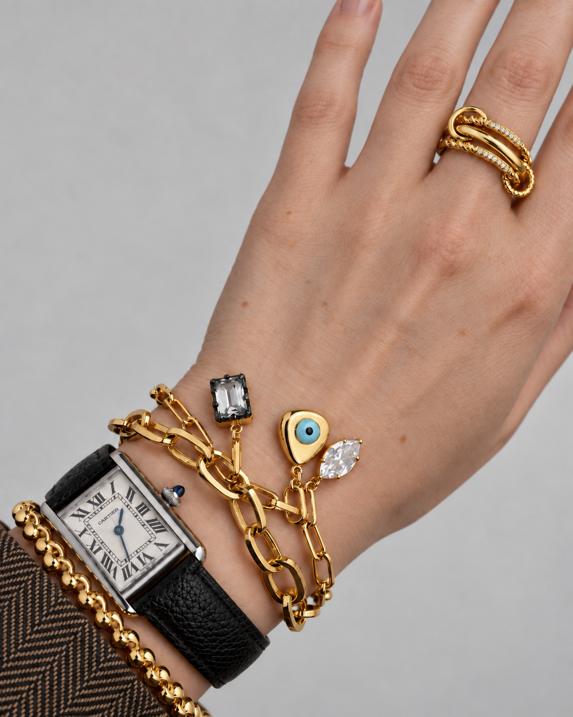 Gold bracelet stack by Galleria Armadoro featuring a chunky Cara chain with Vittoria crystal charms, a blue evil eye charm and layered gold jewellery.