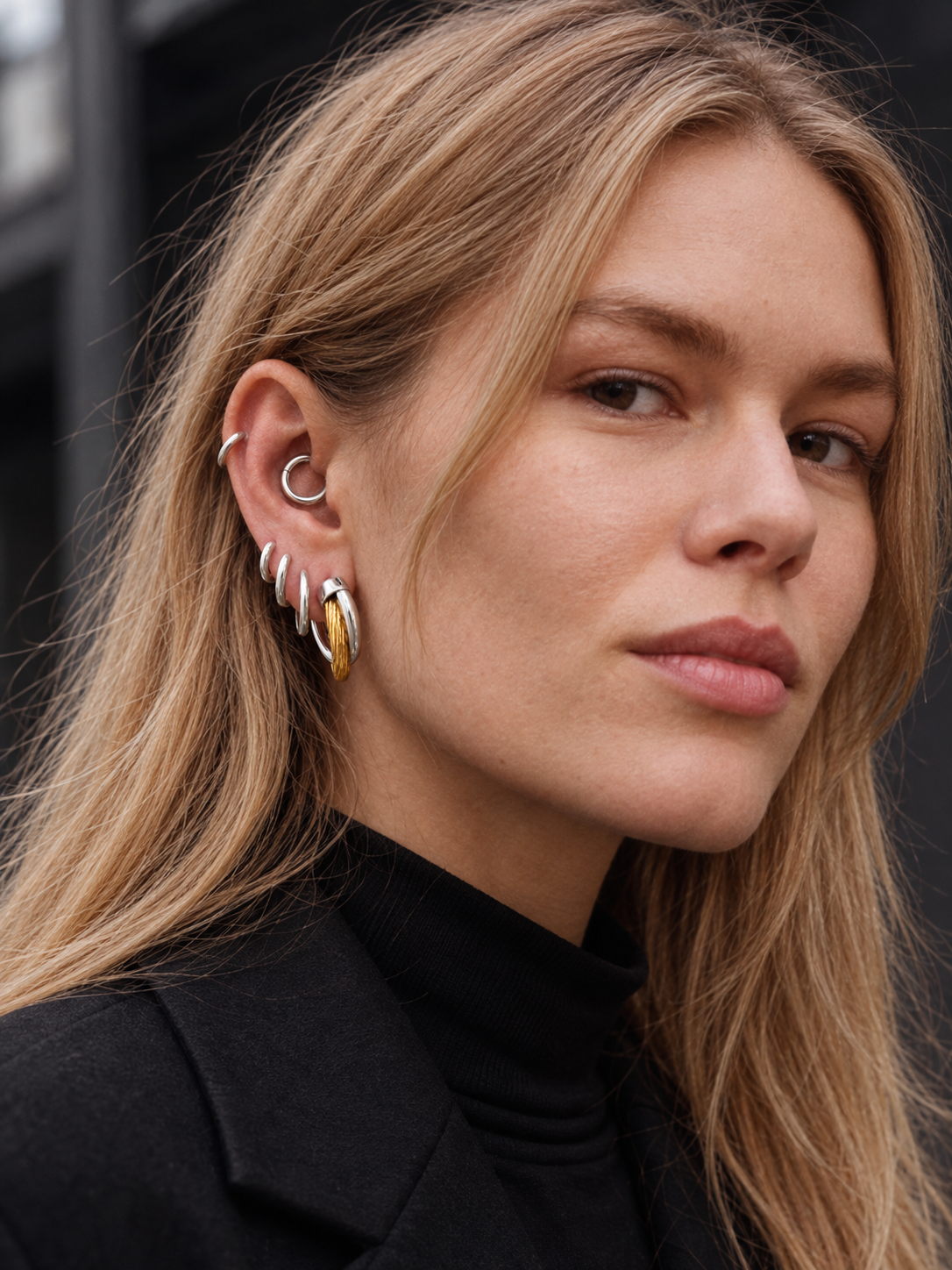 Graduated mixed-metal ear stack by Galleria Armadoro featuring 2 cm Two-Tone Allegra Hoops, silver huggies and an 8.5 mm huggie styled in the daith.