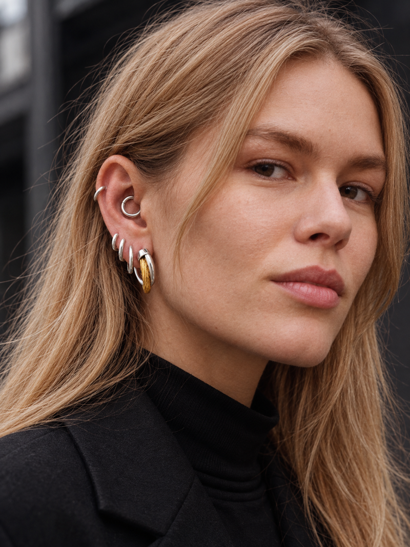 Graduated mixed-metal ear stack by Galleria Armadoro featuring 2 cm Two-Tone Allegra Hoops, silver huggies and an 8.5 mm huggie styled in the daith.