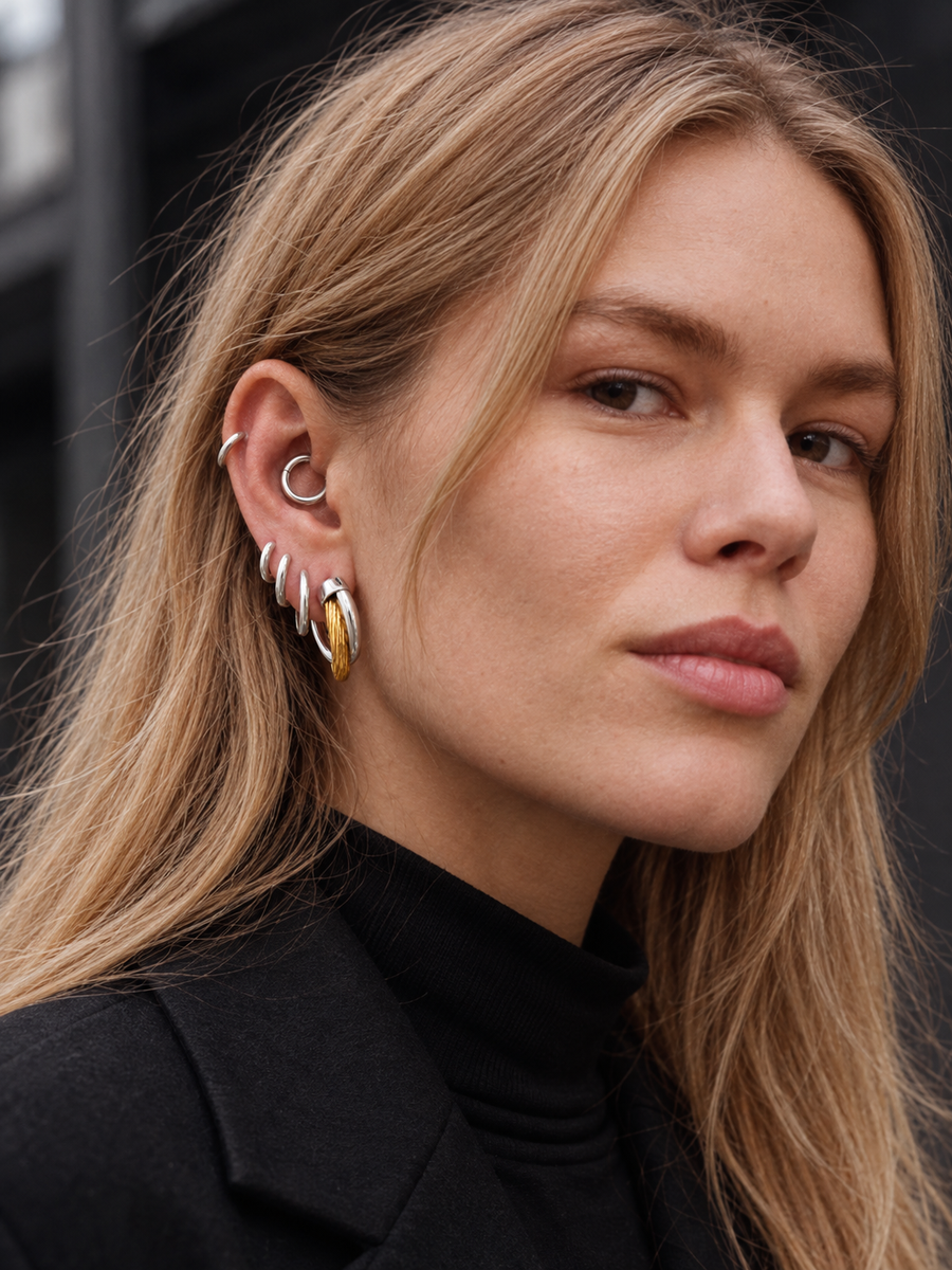 Graduated mixed-metal ear stack by Galleria Armadoro featuring 2 cm Two-Tone Allegra Hoops, silver huggies and an 8.5 mm huggie styled in the daith.