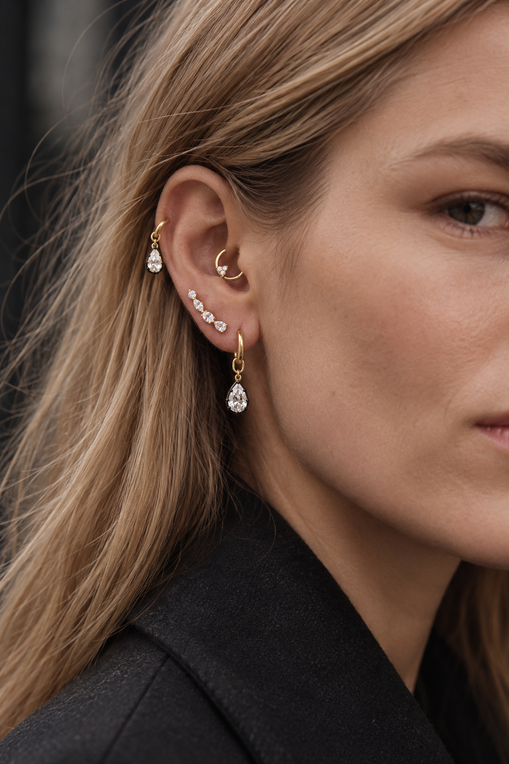 Gold ear stack by Galleria Armadoro featuring removable teardrop charms worn on huggies, a crystal ear climber and a daith clicker.