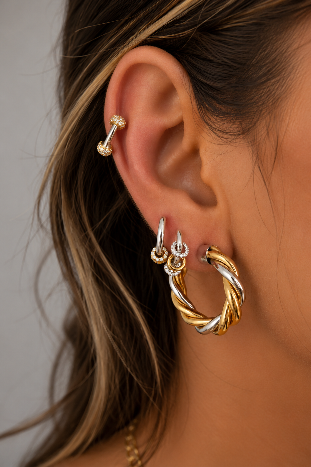 Mixed-metal ear stack by Galleria Armadoro featuring the 3 cm Two-Tone Tinas with smaller gold and silver earrings and a pavé ear piercing.
