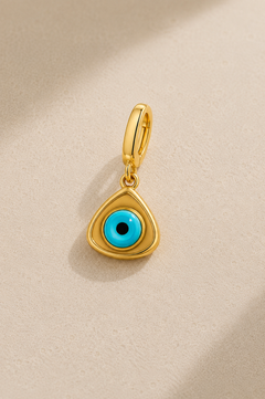 Gold triangle evil eye hook charm with turquoise eye bead on beige studio background