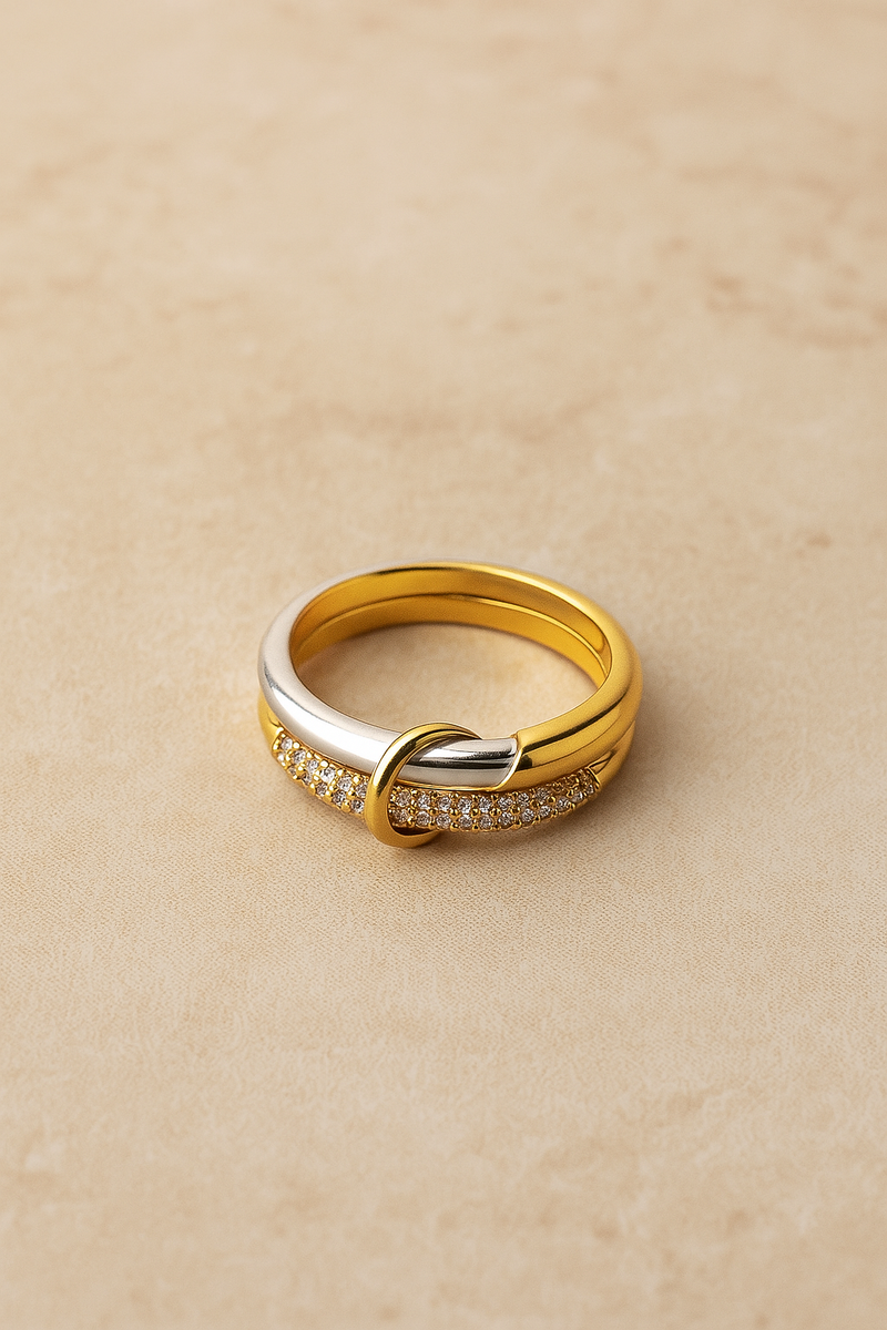 Nora Speira mixed-metal pavé ring on warm beige background, linked bands seen from above.