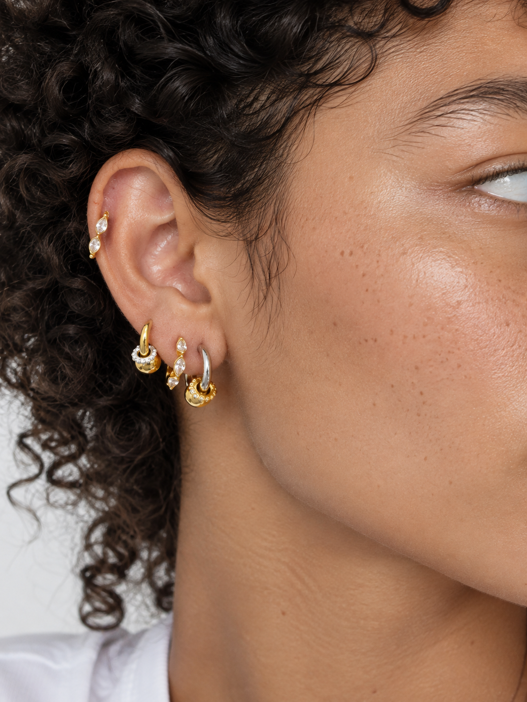 Two-tone ear stack by Galleria Armadoro featuring Kora huggies in gold and silver with Tasha Marquise 8.5 mm and 6.5 mm styled on the helix.