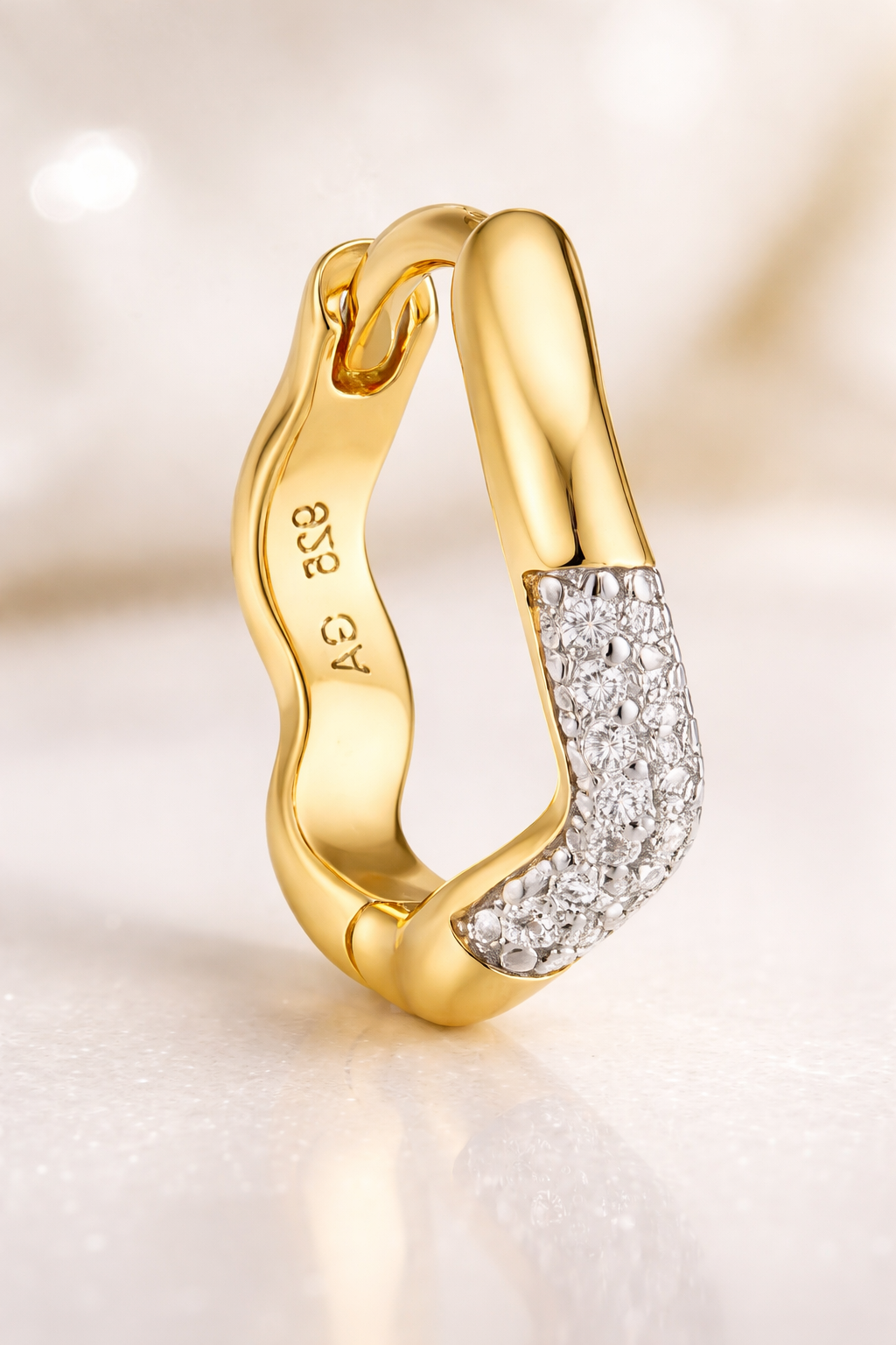 Close-up of Amara Kyma mixed metal huggie earring with white rhodium pavé section