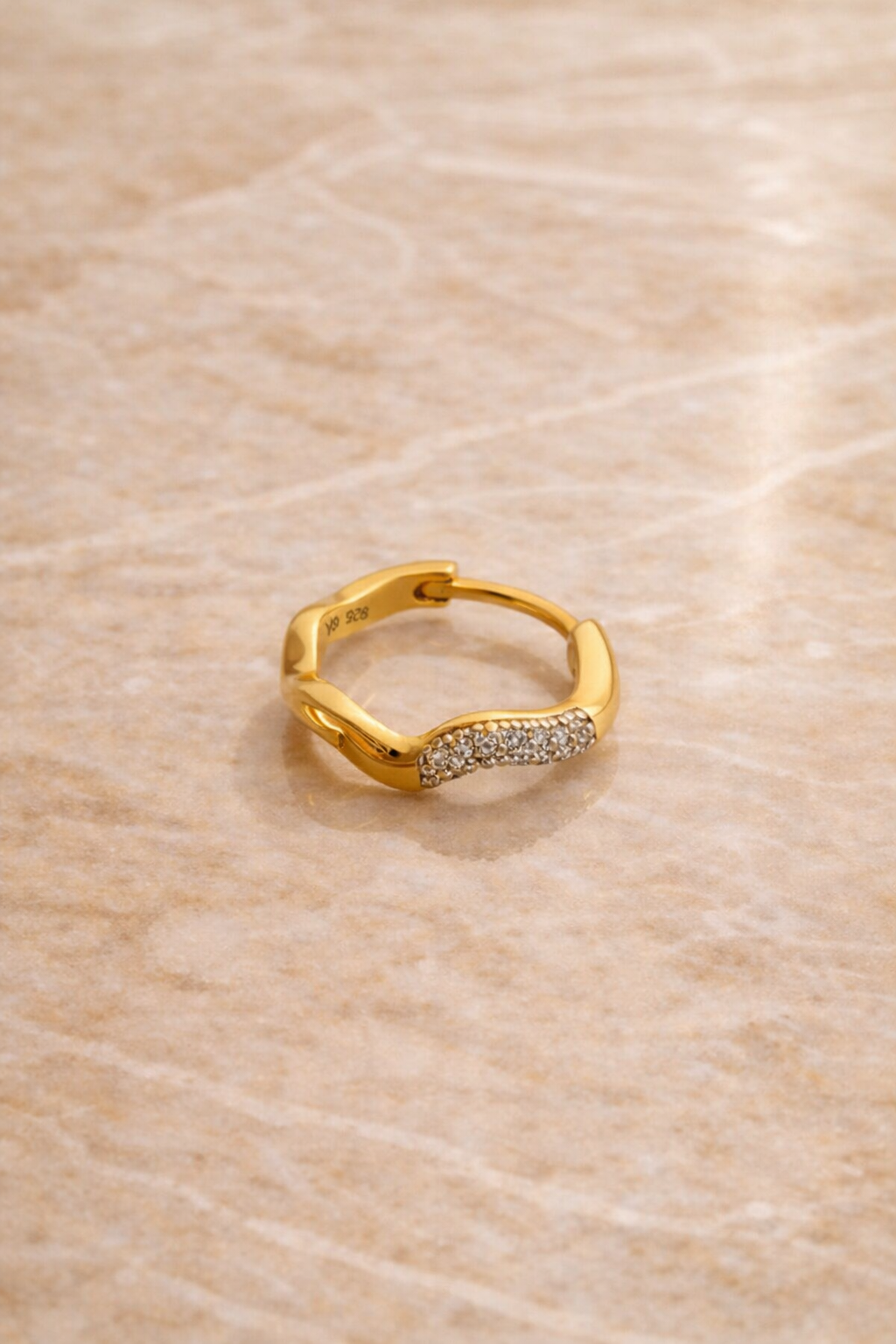 Flatlay of Amara Kyma 10mm two tone sterling silver huggie earring