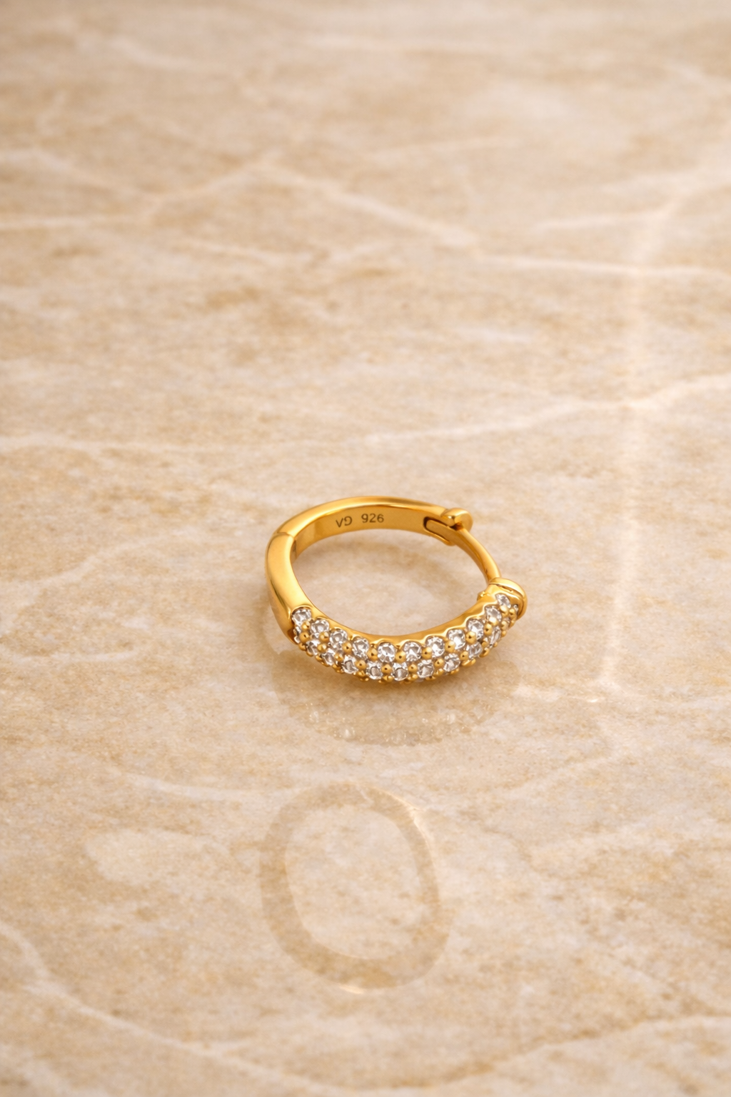 Flatlay of Aurora Kyma 10mm gold plated sterling silver huggie earring