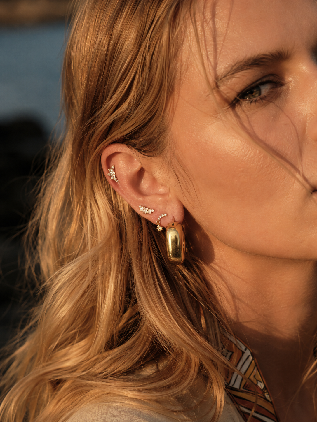 Gold hoop ear stack styled by Galleria Armadoro with a chunky Darla hoop, delicate gold studs and small upper-ear earrings.