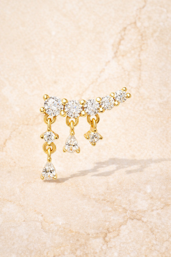 Close-up of drippy croissant gold vermeil stud earring with curved crystal row and dangling teardrop stones