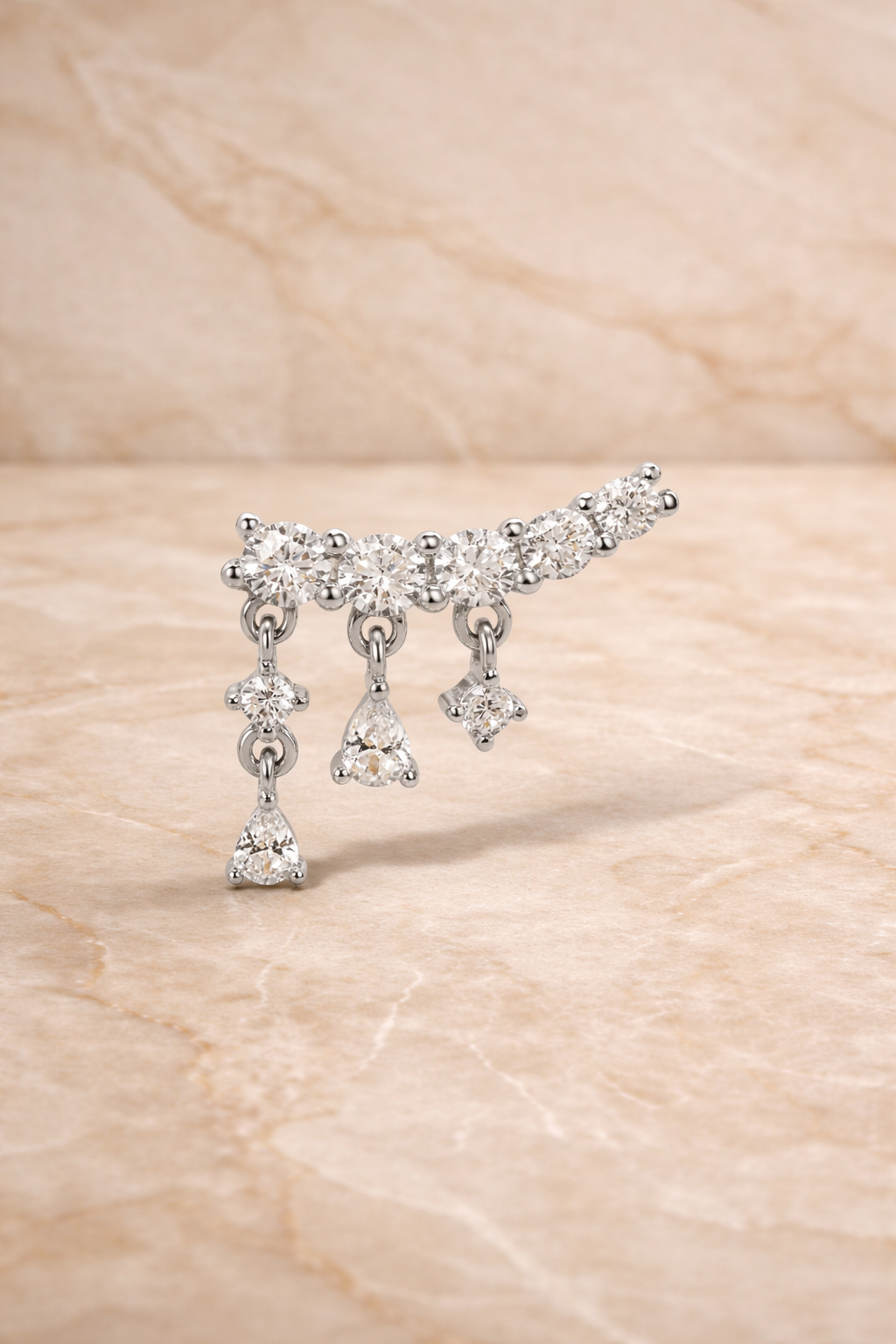 Close-up of drippy croissant sterling silver stud earring with curved row of crystals and dangling drops