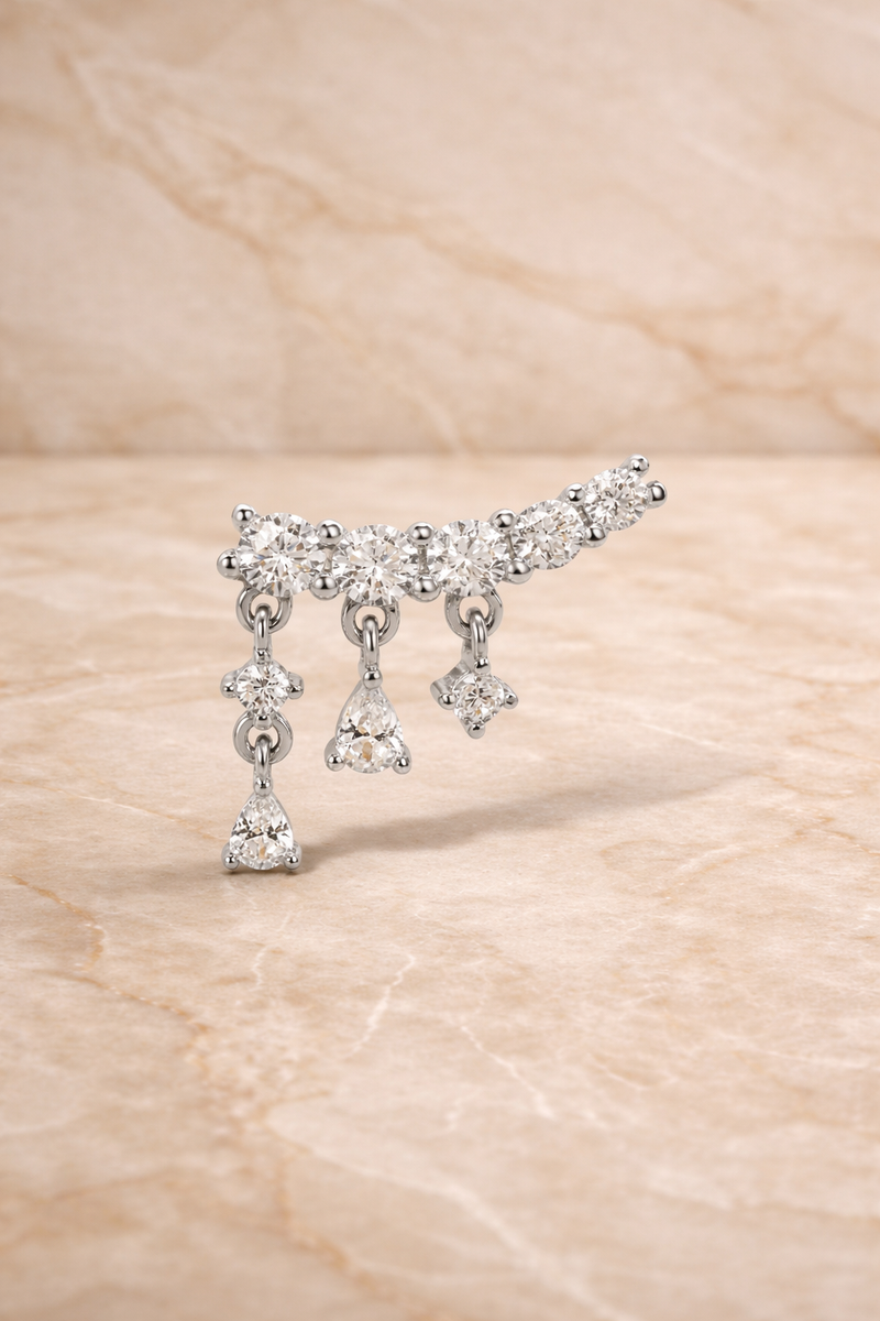 Close-up of drippy croissant sterling silver stud earring with curved row of crystals and dangling drops