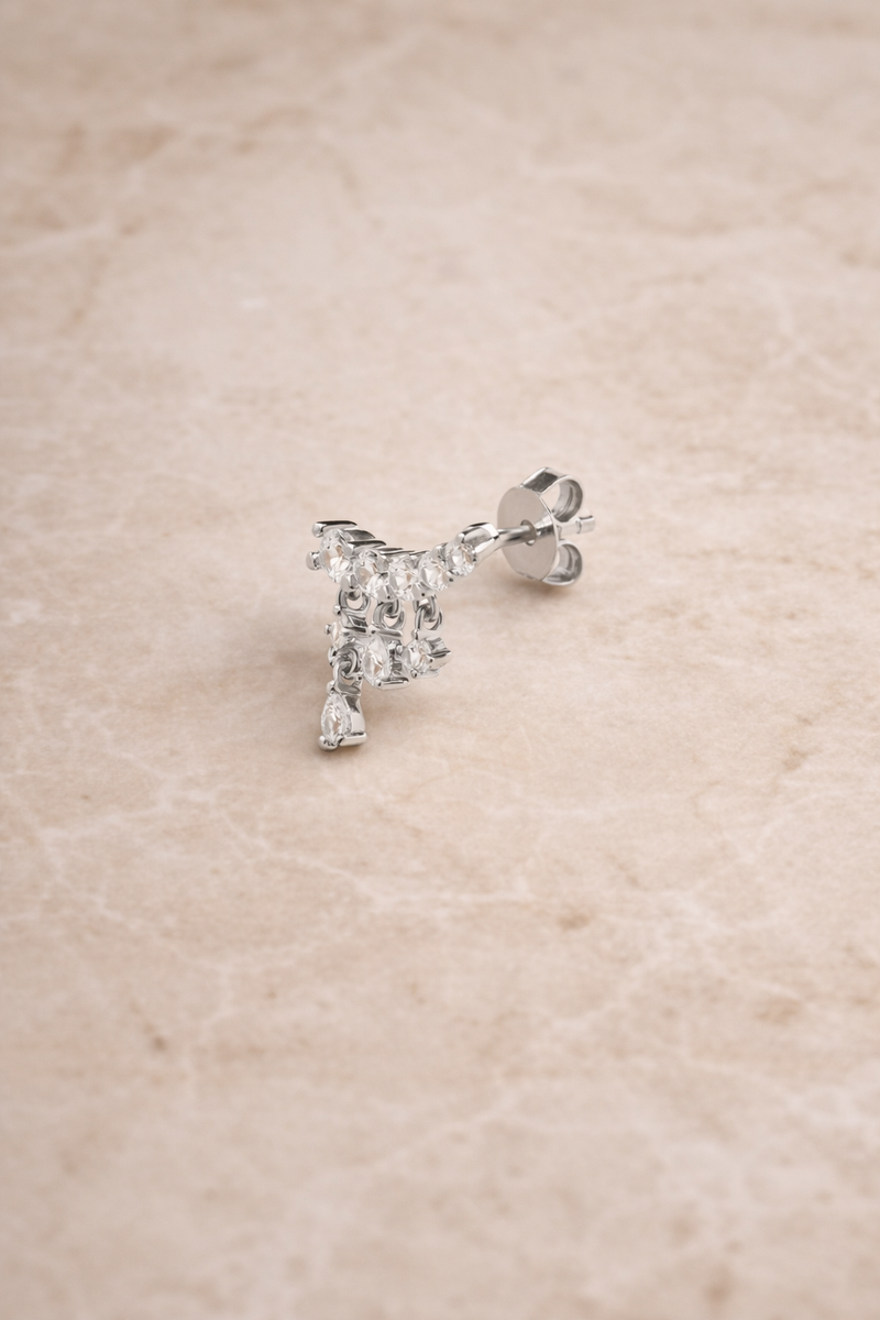 Drippy croissant sterling silver stud earring with cascading crystal drops photographed on beige marble background