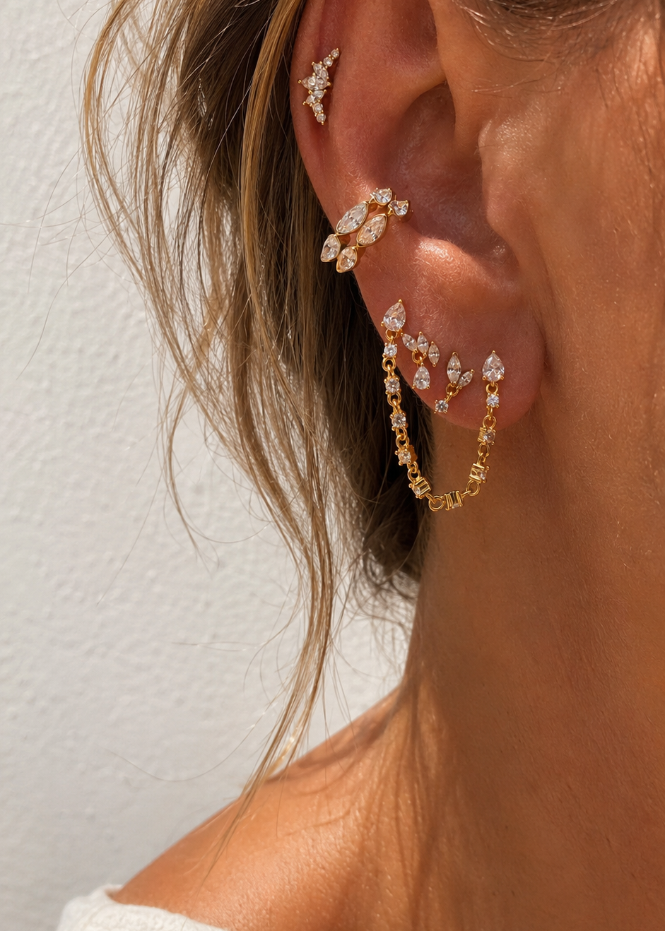Layered gold ear stack styled by Galleria Armadoro with marquise earrings, linked chain details and sculptural upper-ear placements.
