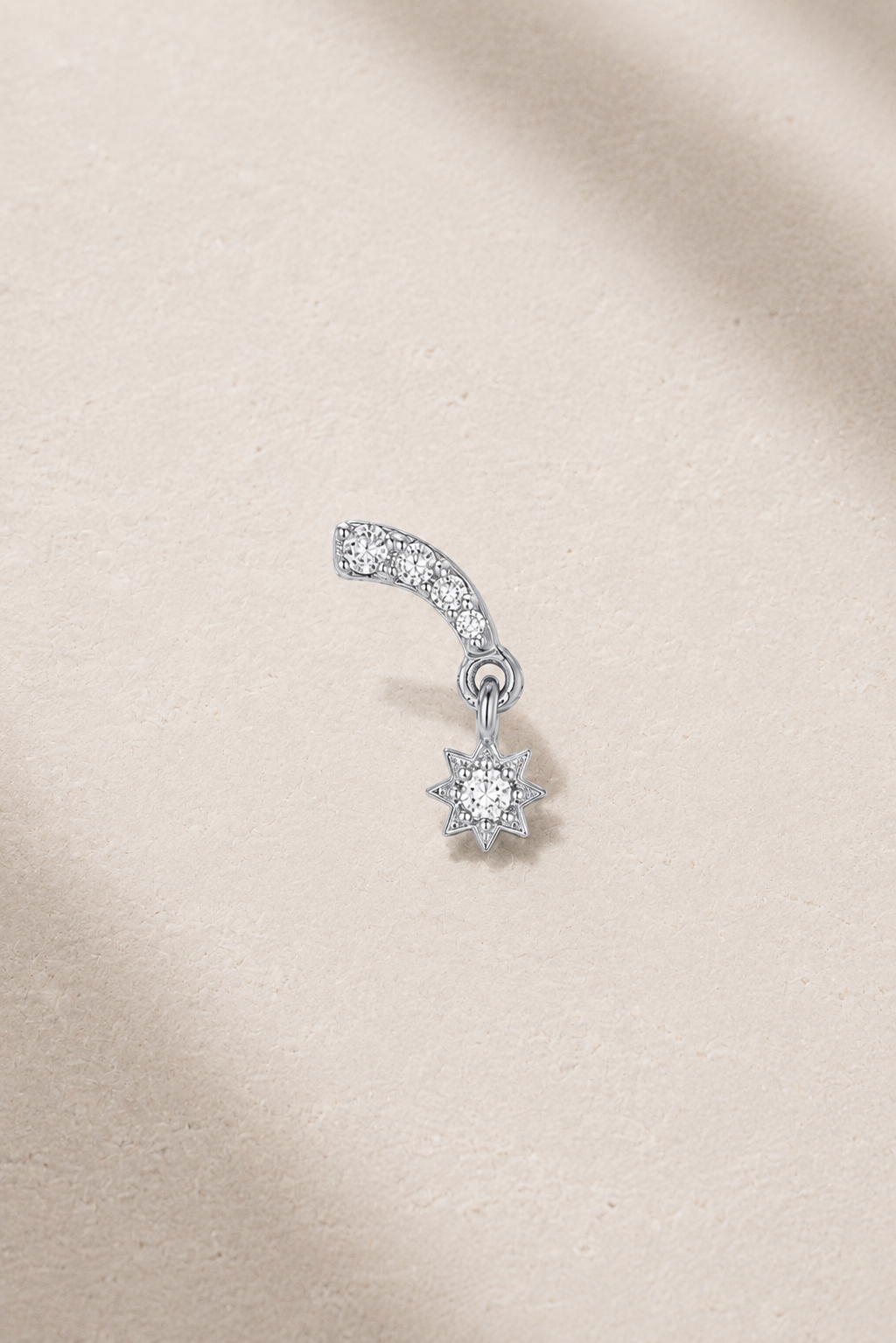 Celestial-inspired silver stud earring with white CZ stones on neutral stone background