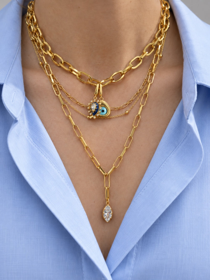 Layered gold necklace look by Galleria Armadoro featuring protective eye charms, mixed chain weights and a long marquise crystal charm.