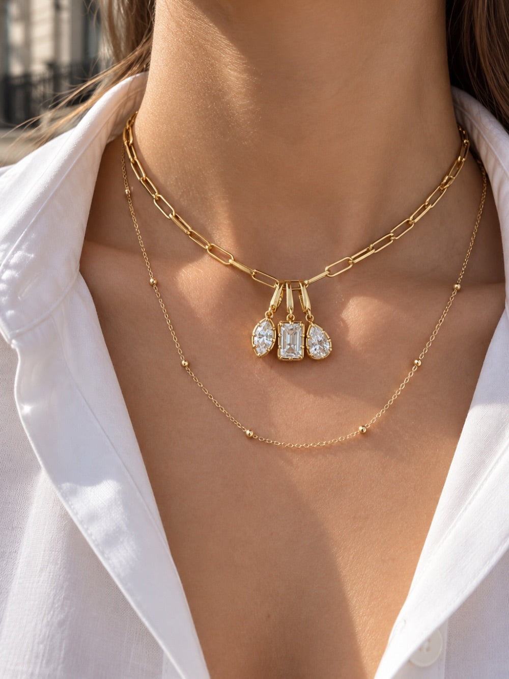 Layered gold necklace look by Galleria Armadoro featuring a triple Vittoria charm necklace and the Charlotte Beaded Station Chain worn underneath.