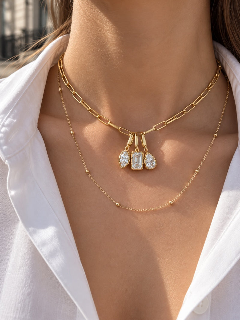 Layered gold necklace look by Galleria Armadoro featuring a triple Vittoria charm necklace and the Charlotte Beaded Station Chain worn underneath.