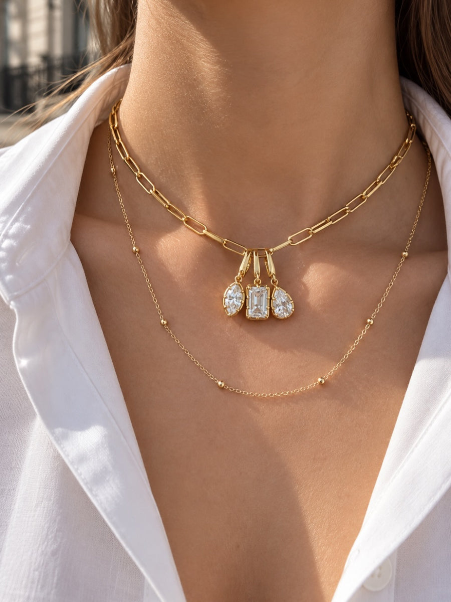 Layered gold necklace look by Galleria Armadoro featuring a triple Vittoria charm necklace and the Charlotte Beaded Station Chain worn underneath.