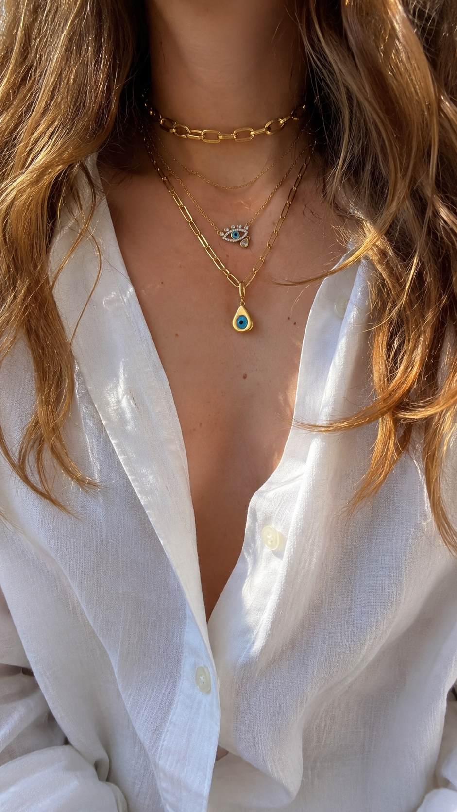 Layered gold necklaces by Galleria Armadoro with the Cara Chain worn at 35 cm, Large Link Gold Chain at 40 cm and layered evil eye charms.