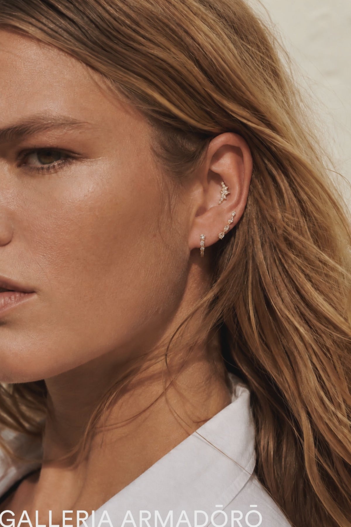 Delicate gold ear stack styled by Galleria Armadoro with pavé huggies, curved earrings and sculptural upper-ear placements.