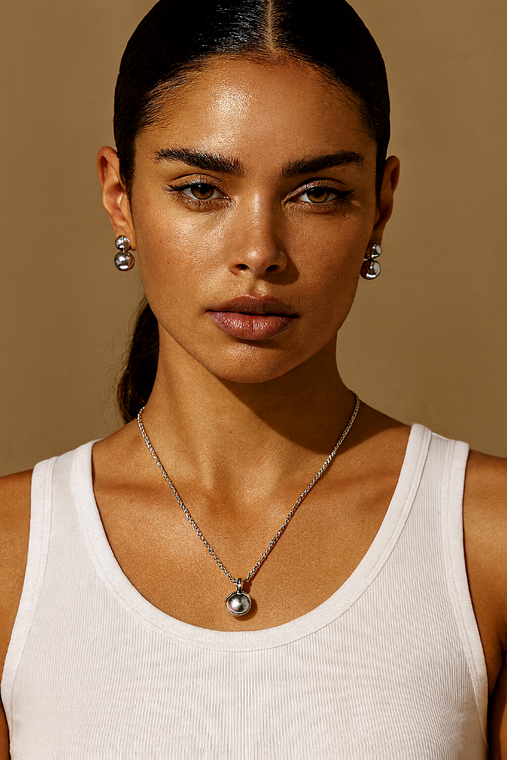 Riva sphere pendant necklace in white rhodium plated silver tone worn on neck, special-design chain with matching earrings