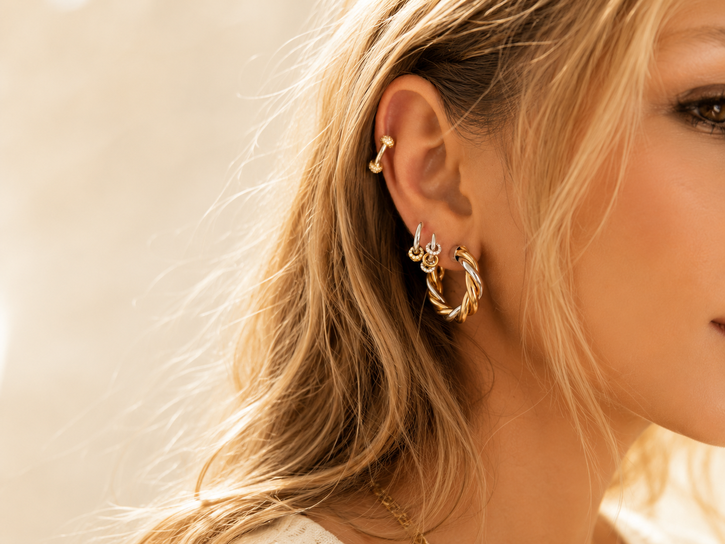 Mixed-metal hoop earring stack styled by Galleria Armadoro with sculptural gold and silver twisted hoops, huggies and pavé ear details.