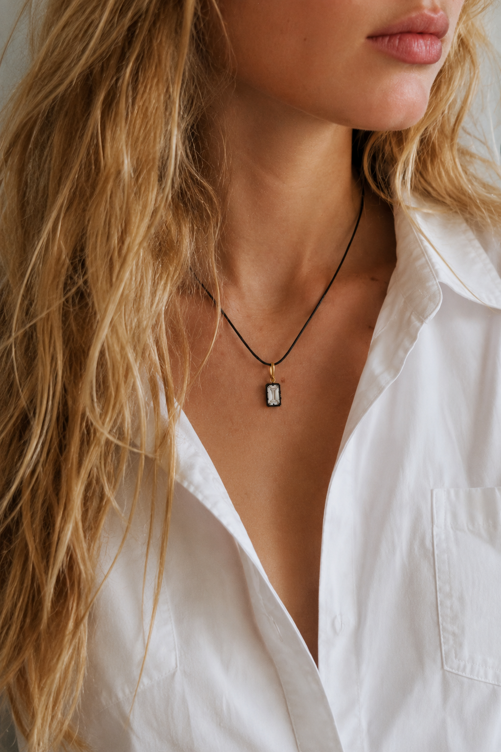 Model wearing adjustable black cord necklace with Vittoria emerald-cut hook charm in 24ct gold and black rhodium