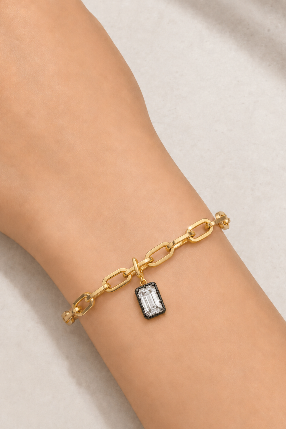Model wearing the Cara gold plated bracelet with Vittoria Emerald Cut black rhodium and gold hook charm