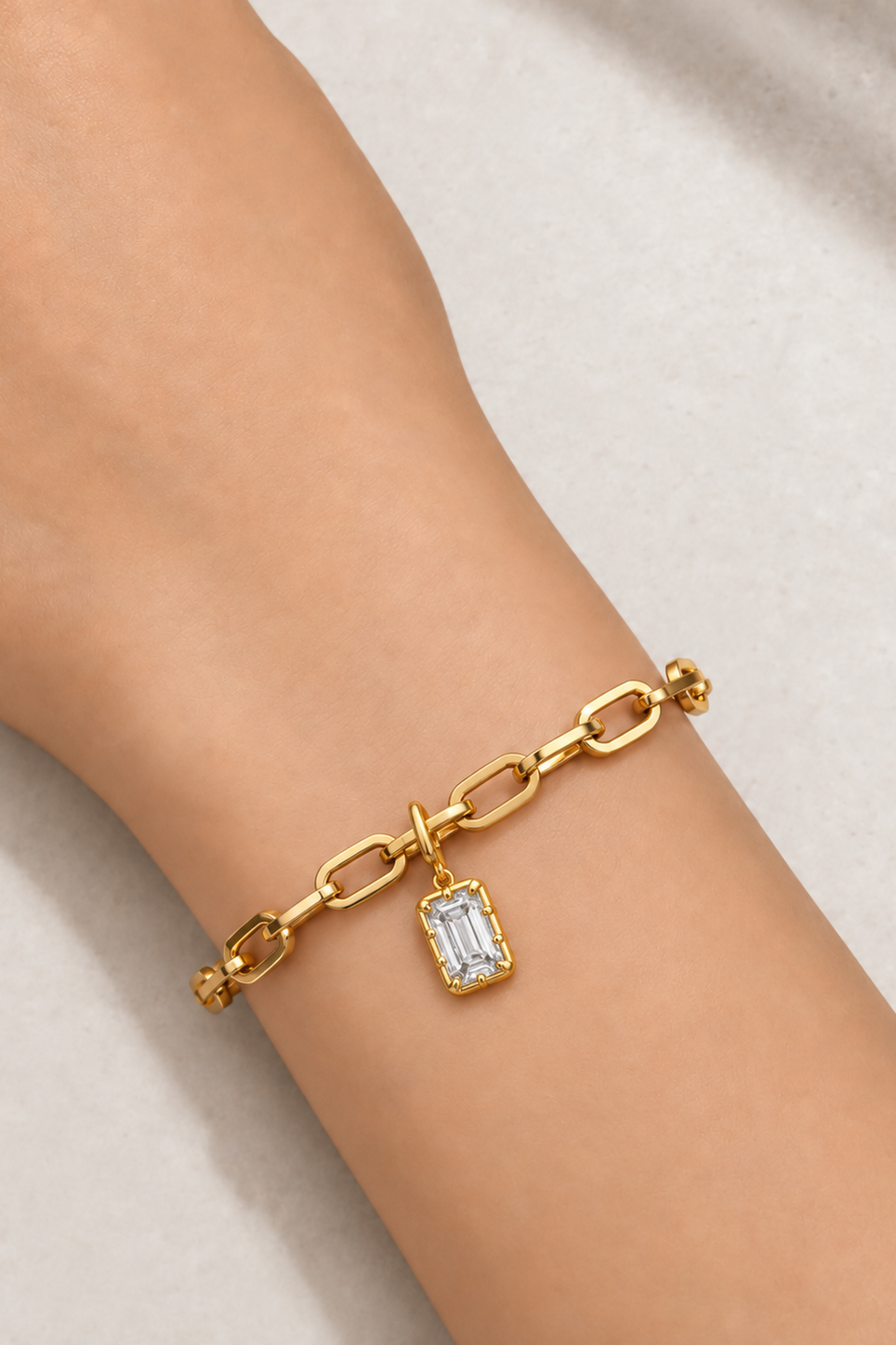 Model wearing the Cara gold plated bracelet with Vittoria Emerald Cut gold hook charm