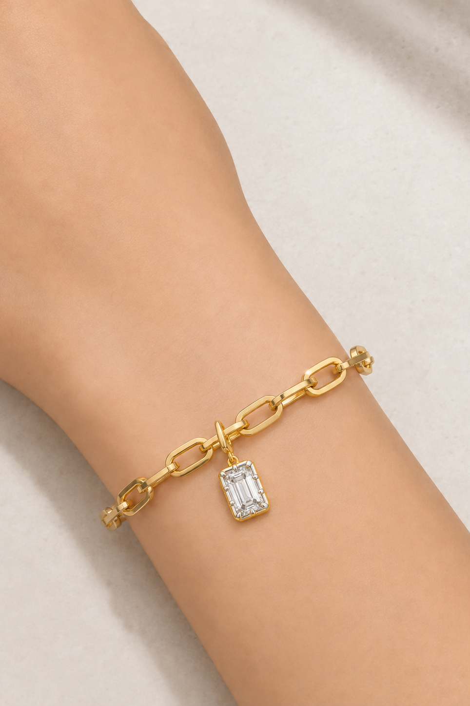 Model wearing the Cara gold plated bracelet with Vittoria Emerald Cut white rhodium and gold hook charm