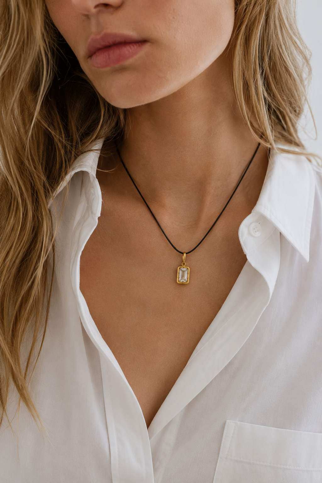 Model wearing adjustable black cord necklace with Vittoria emerald-cut 24ct gold plated hook charm