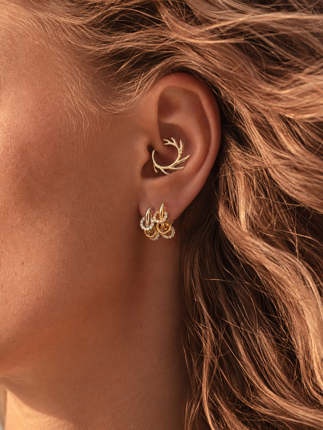 Mixed-metal ear stack styled by Galleria Armadoro with a sculptural gold Ellara daith earring and gold and silver Yasmin lobe earrings.